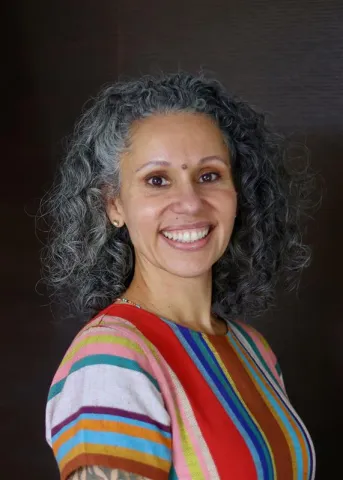 Karina Vernon woman in striped coloured shirt with gray wavy hair smiling