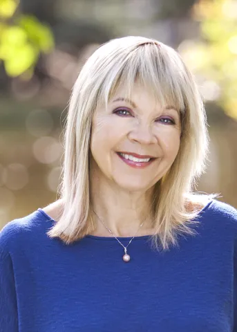Smiling woman with blank shoulder length hair wearing a blue shirt