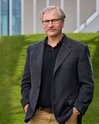 Dr. Robert Gruninger (BSc ’05, PhD ’09) stands in front of ULethbridge 