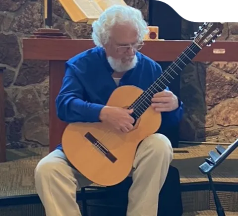 Dale Ketcheson seated playing the acoustic guitar.