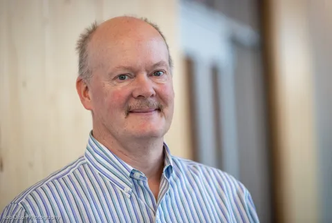 man in a stripped button up in front of a door