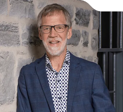 Photo of John Burge standing in front of a limestone wall.