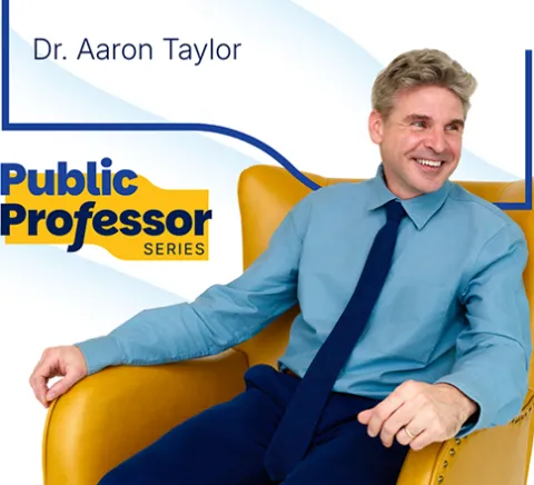 Public Professor Series. Dr. Aaron Taylor is sitting in a yellow chair.