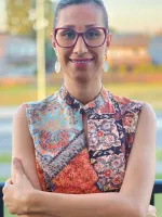 Woman with glasses standing with smile on her face.