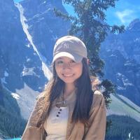 Female student smiling in-front of lake and tree