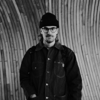 black and white image of a man wearing a black hat and jacket