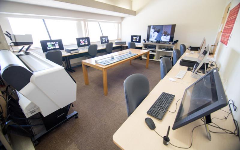 Room with computer workstations, tablets, and printers