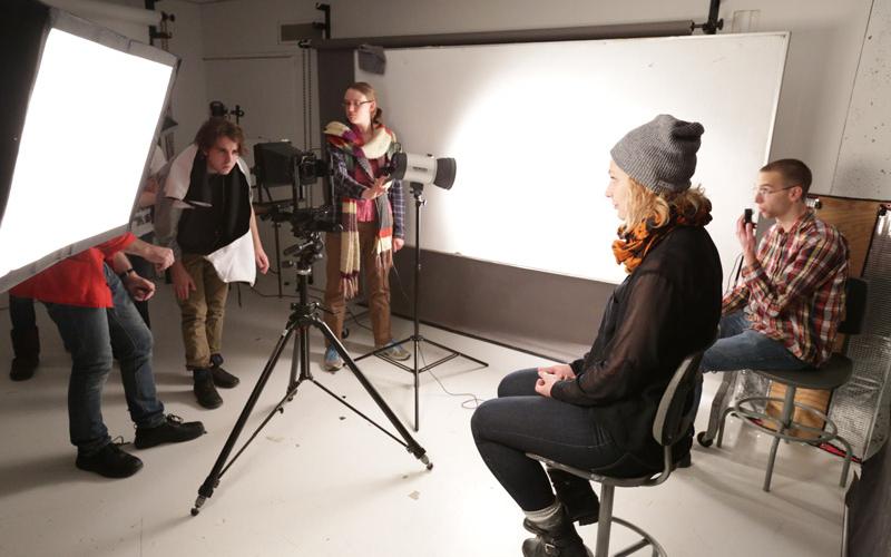 Student sitting on stool for photoshoot