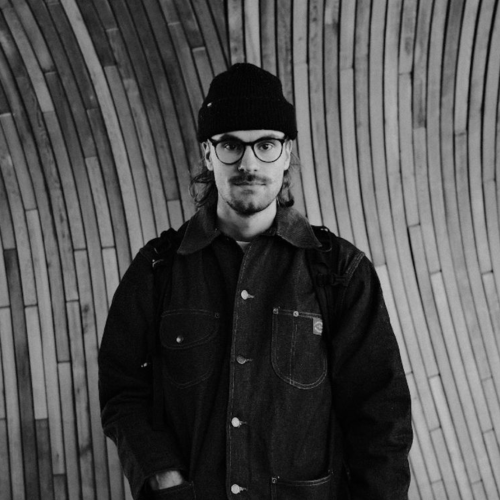 black and white image of a man wearing a black hat and jacket