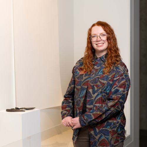 Kiara Pike stands in front of an art exhibit