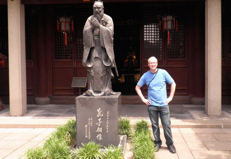 Aaron Eelhart poses next to a statue of Confucious at the Shanghai Confucious Temple