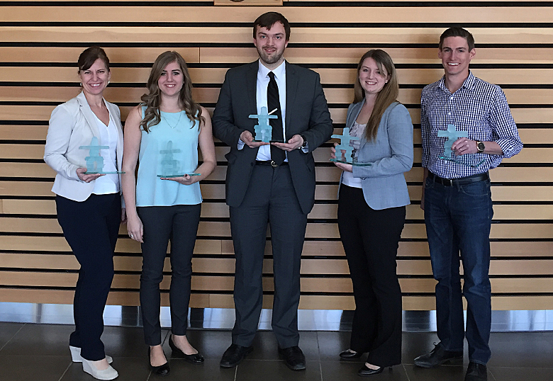 Erin Crane (at left), industry advisor, Katherine Colburn-Swartz, team member, Alex Glydon, team member, Jacquelyn Walker, team member and Matt Calnan, industry advisor, hold the Inukshuk trophies they earned as first-place finishers in the KPMG Management Case Competition.